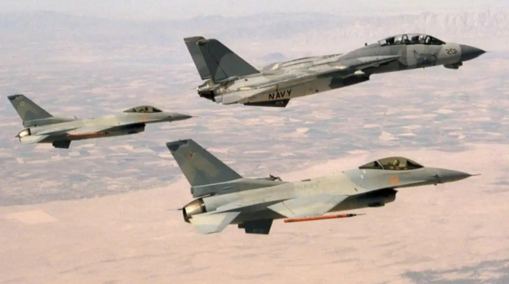 Un caccia imbarcato F-14 Tomcat della Marina statunitense vola in formazione serrata con due rari F-16N appartenenti al reparto Aggressor della scuola Top Gun. La foto mette perfettamente in risalto la configurazione aerodinamica "pulita" delle due Vipere, completamente prive di piloni subalari e armamento interno per massimizzare l'agilità nei duelli simulati. (Foto: U.S. Navy)