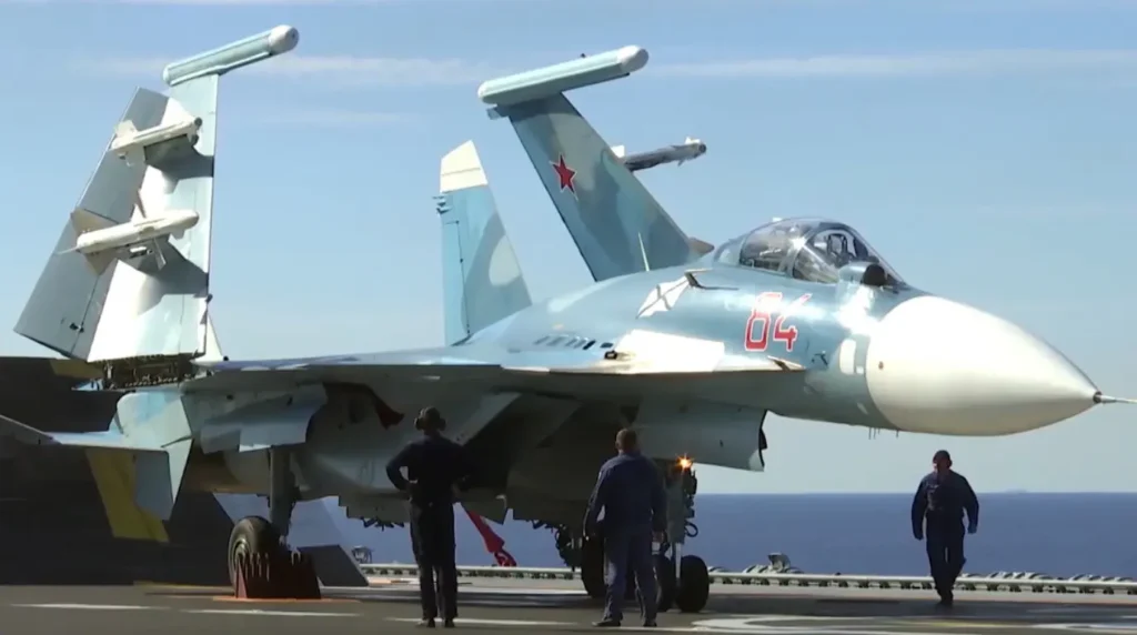 Un caccia multiruolo imbarcato Sukhoi Su-33 (Red 04) posizionato sul ponte della portaerei Ammiraglio Kuznetsov con le ali ripiegate in configurazione da hangar.Foto: Ministero della Difesa della Federazione Russa (Mil.ru)