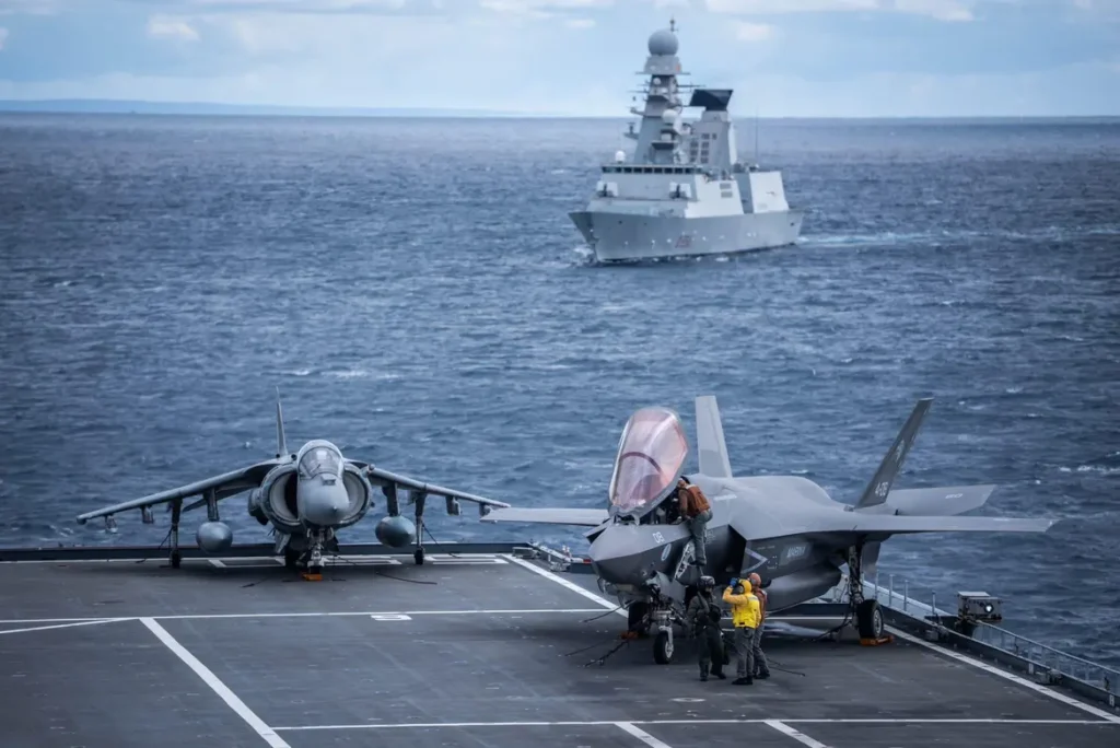 L'immagine mostra un caccia di quinta generazione F-35B e un AV-8B Harrier II sul ponte di volo della portaerei italiana Cavour (ITS Cavour), durante un'attività operativa della Marina Militare.