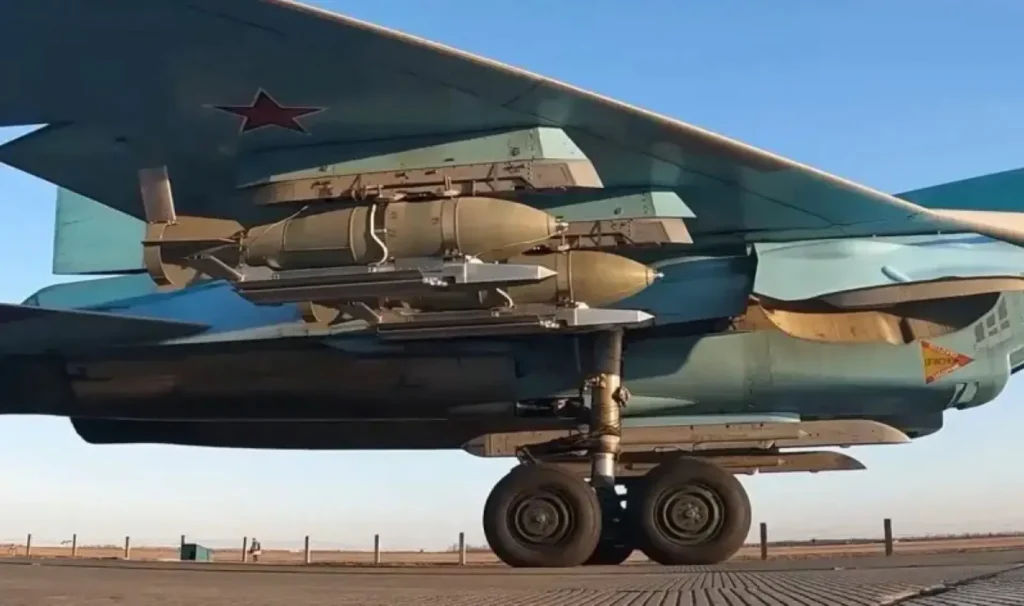 Vista ravvicinata del carrello e della semi-ala di un cacciabombardiere Su-34 armato con bombe plananti dotate di kit UMPK.