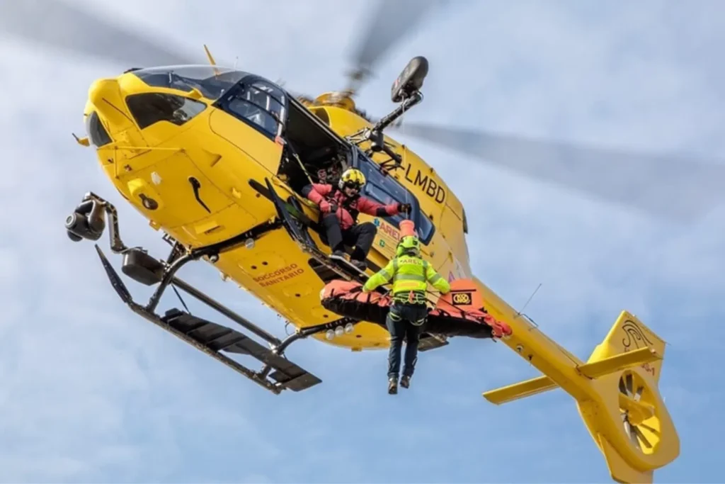 Un elicottero Airbus Helicopters H145 / EC145 T2 (marche I-LMBD), denominato "Horus 1" e operato da Avincis Aviation Italia per conto dell'AREU (Agenzia Regionale Emergenza Urgenza) della Regione Lombardia presso la base di Bergamo (Ospedale Papa Giovanni XXIII). Lo scatto ravvicinato ravvisa lo specialista degli impianti di bordo e un tecnico del Soccorso Alpino pronti alle operazioni esterne con la barella sospesa al verricello, recando chiaramente sulla fusoliera la scritta "Soccorso Sanitario".