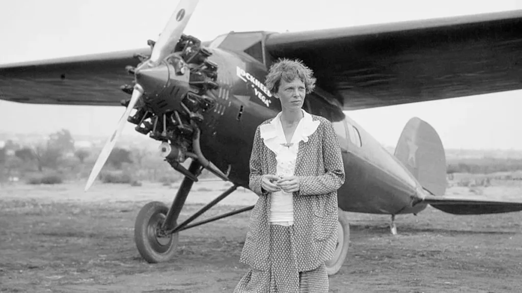  Amelia Earhart in piedi davanti al suo iconico aeroplano, un Lockheed Vega 5B. 