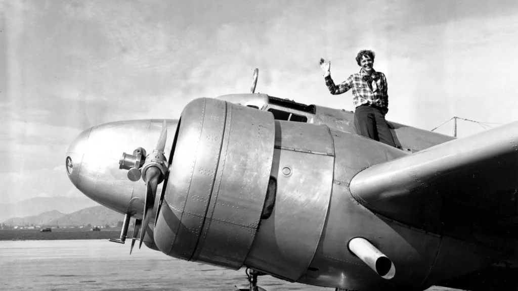 Amelia Earhart mentre saluta in piedi sul motore del suo aereo, un Lockheed Model 10-E Electra, a Los Angeles il 10 marzo 1937, poco prima del suo tentativo di giro del mondo.