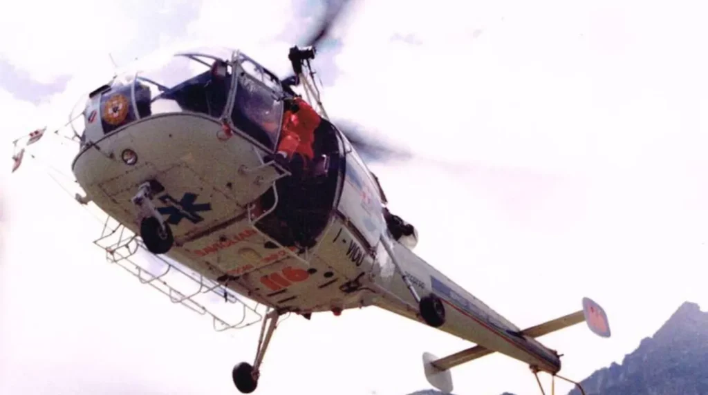 L'inaugurazione della prima base alpina dell'elisoccorso piemontese presso l'Ospedale di Savigliano (CN), avvenuta l'11 agosto 1988. Il velivolo ritratto è un Aérospatiale SA 316B Alouette III (marche I-VIOU) operato dalla compagnia EliAlpi. Il mezzo presenta sotto la cabina il numero di attivazione 116 dell'epoca, legato alla storica collaborazione con l'Automobile Club d'Italia (ACI), e sul muso reca la stella della vita blu accanto alla scritta "Savigliano".